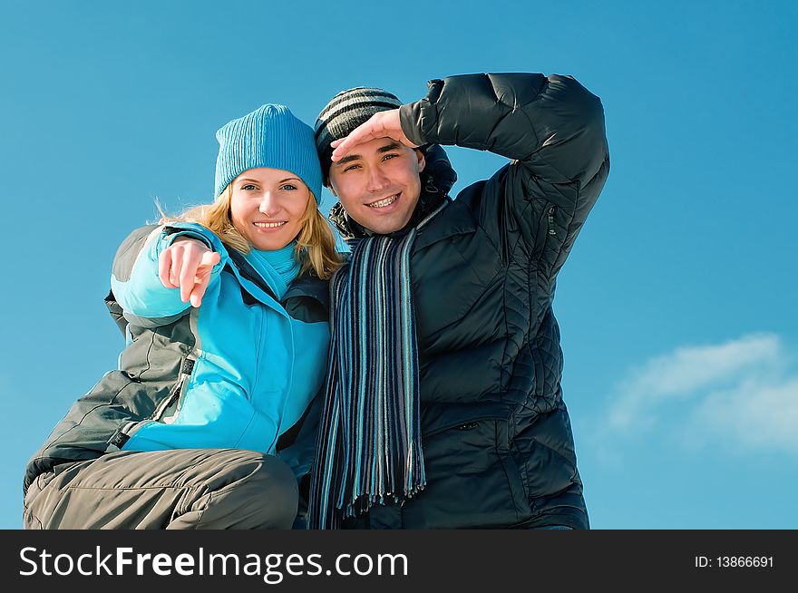 The young guy and girl on a background of the sky looks in a distance in the winter. The young guy and girl on a background of the sky looks in a distance in the winter