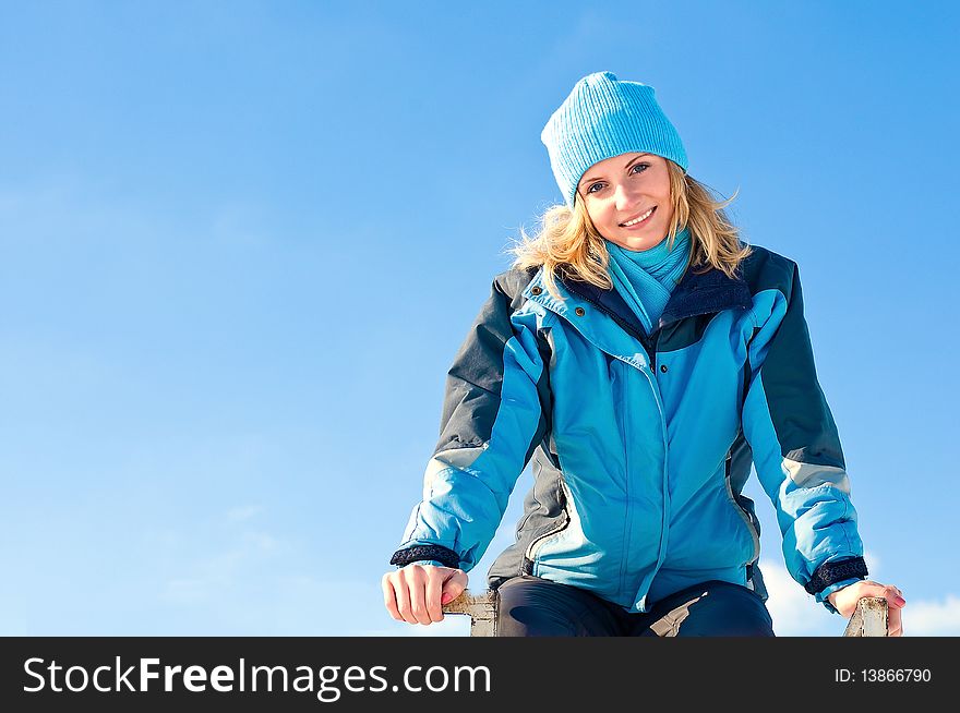 The young girl  on a background of the sky looks in a distance in the winter