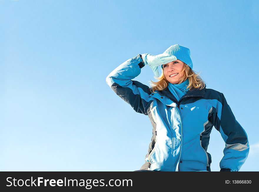 The young girl on a background of the sky looks in a distance in the winter