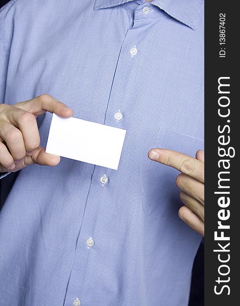 Business young man in a blue shirt holding a blank business card. The other hand points a finger. Business young man in a blue shirt holding a blank business card. The other hand points a finger