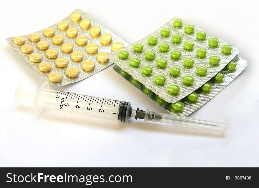 A medical syringe and tablets are on the image. A medical syringe and tablets are on the image.