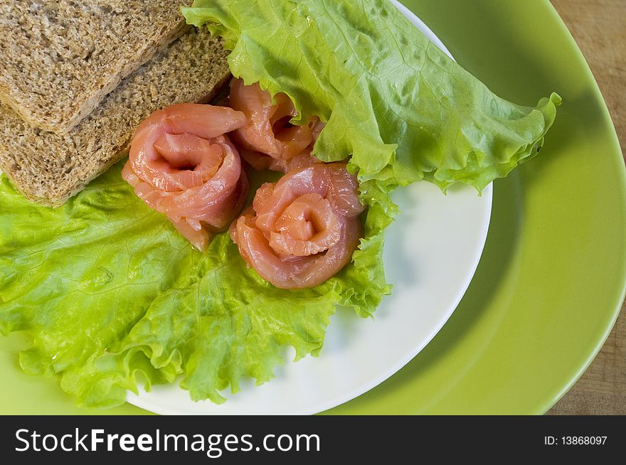 Slices of bread and three slices of a salmon on a white plate. Slices of bread and three slices of a salmon on a white plate