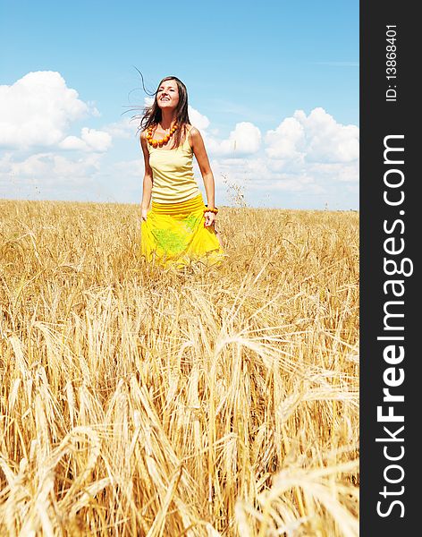 Beautiful young girl playing on a wheat field on a sunny day