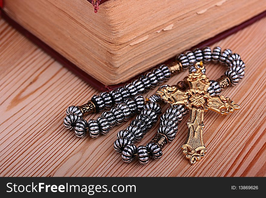 Religion. A cross with a chain against a wooden table. Religion. A cross with a chain against a wooden table.