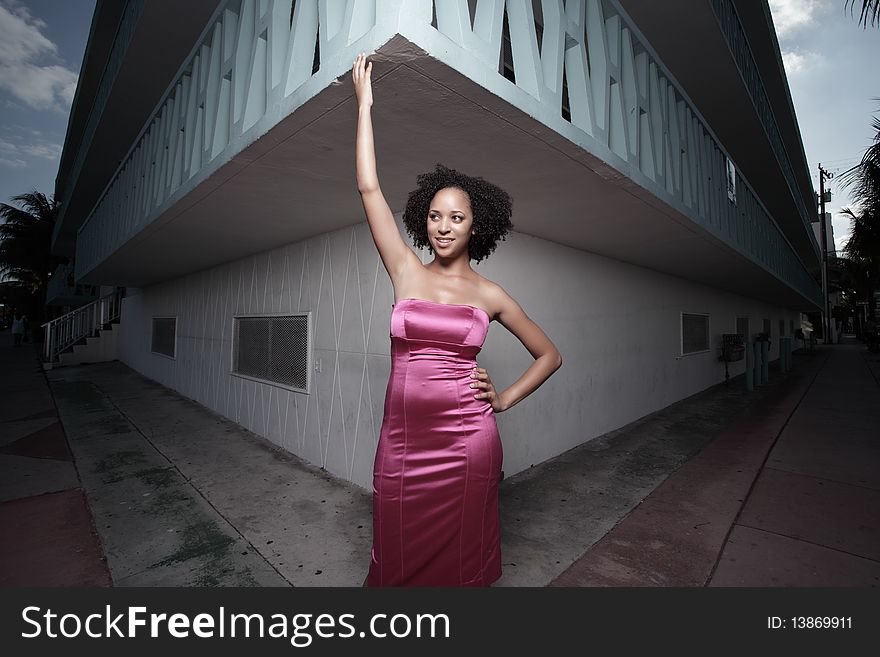 Young woman posing by a building corner