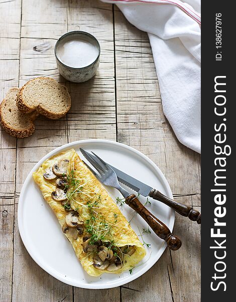 Vegetarian breakfast, omelette with mushrooms and cress, served with rye bread and coffee with milk. Rustic style