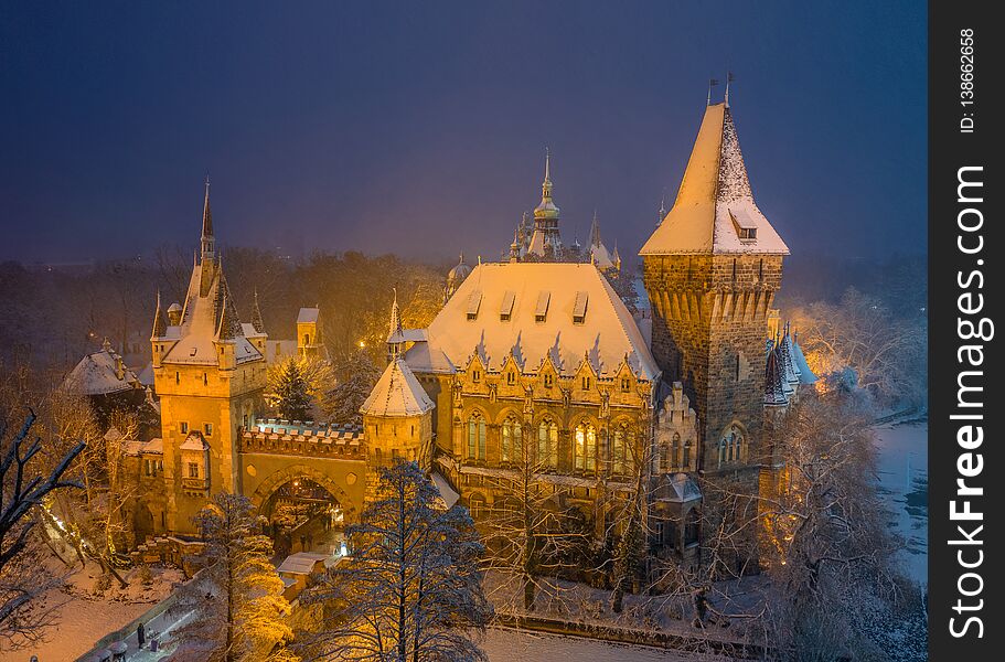 Budapest, Hungary - Aerial winter scene of the beautiful Vajdahunyad Castle in snowy City Park at blue hour during snowing