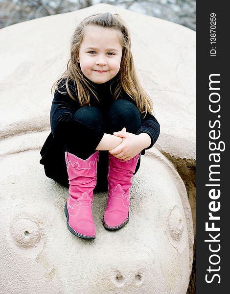 Adorable girl posing on top of a turtle sculpture in hot pink leather boots. Adorable girl posing on top of a turtle sculpture in hot pink leather boots.