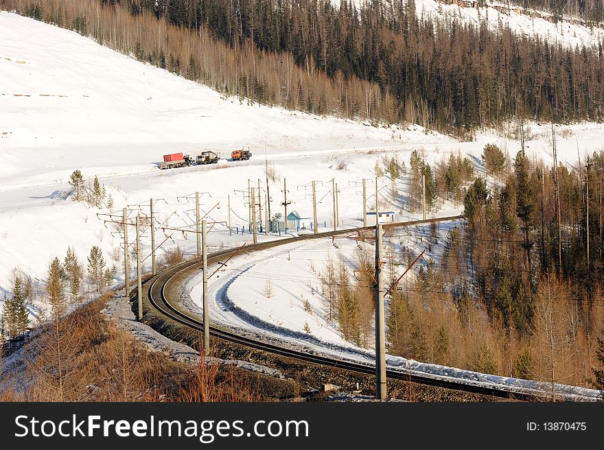 The railway in the winter bent between snow mountains