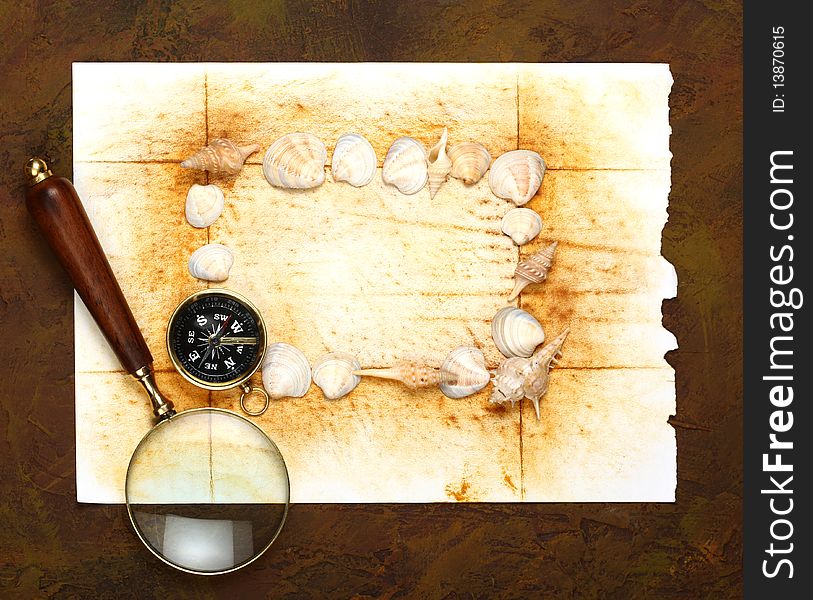 Compass and magnifier  on old textured paper with sea cockleshells. Compass and magnifier  on old textured paper with sea cockleshells