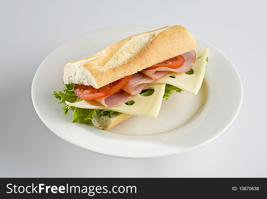 Ham and Swiss cheese baguette on white plate