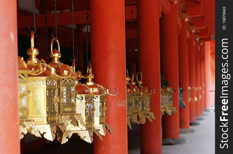 Golden Lanterns hang between red pillars at a Shinto Temple in Nara, Japan's ancient capital. Golden Lanterns hang between red pillars at a Shinto Temple in Nara, Japan's ancient capital.