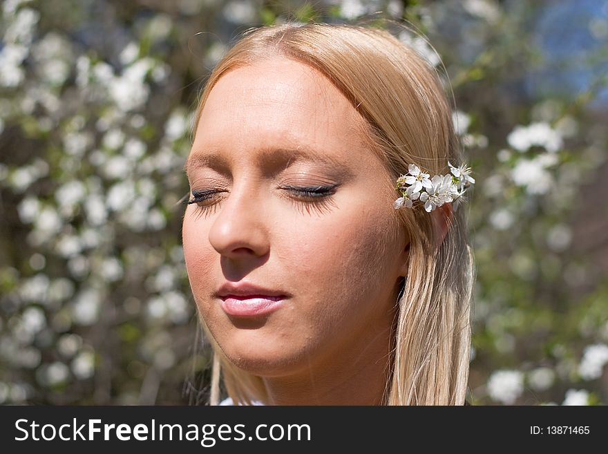 Blond girl in front of blossomed tree on early spring