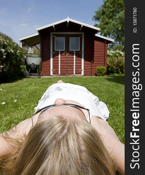 Teenage girl lying relaxed on grass in the garden.