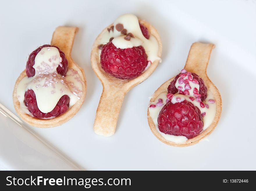 A trio of pastry spoons topped with raspberries, white chocolate & sprinkles. A trio of pastry spoons topped with raspberries, white chocolate & sprinkles