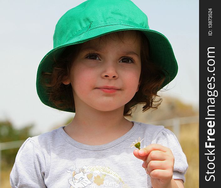 Little girl wearing a hat and holding a flower. Little girl wearing a hat and holding a flower