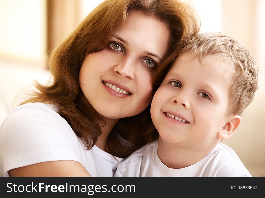 Happy young mother hugging her little son at home