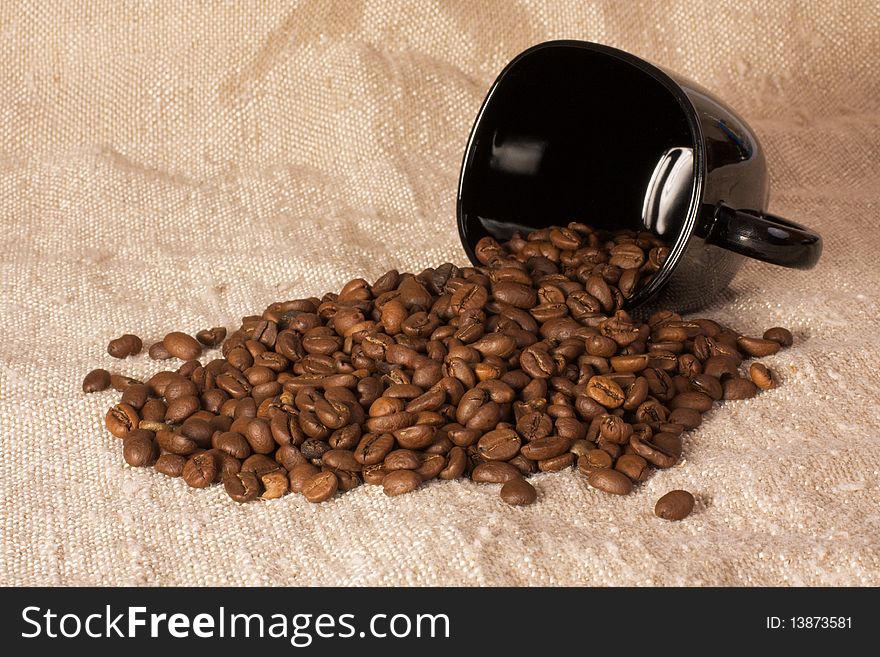 Mug with coffee beans on the rustic canvas