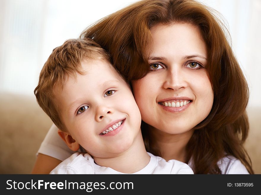 Happy young mother hugging her little son indoor