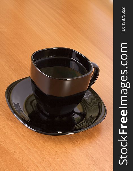 Black cup and plate on the wooden table. Black cup and plate on the wooden table