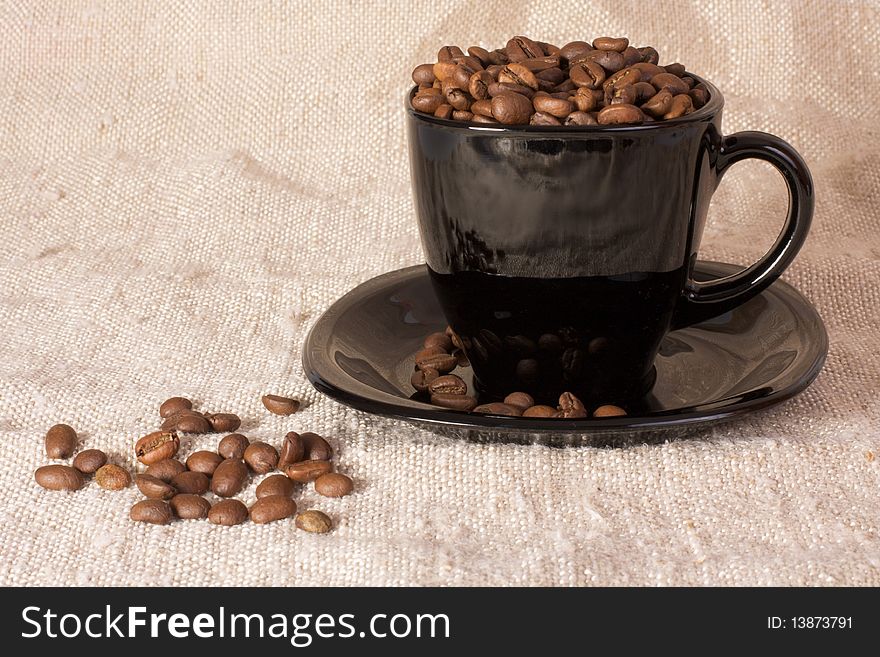 Mug with coffee beans on the rustic canvas