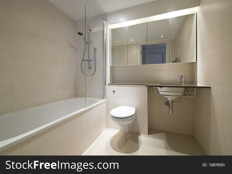 Modern bathroom with a designer wash basin and bath tub in beige