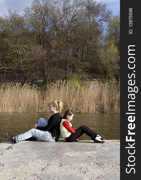 Cute girl with woman sitting near a lake. Cute girl with woman sitting near a lake