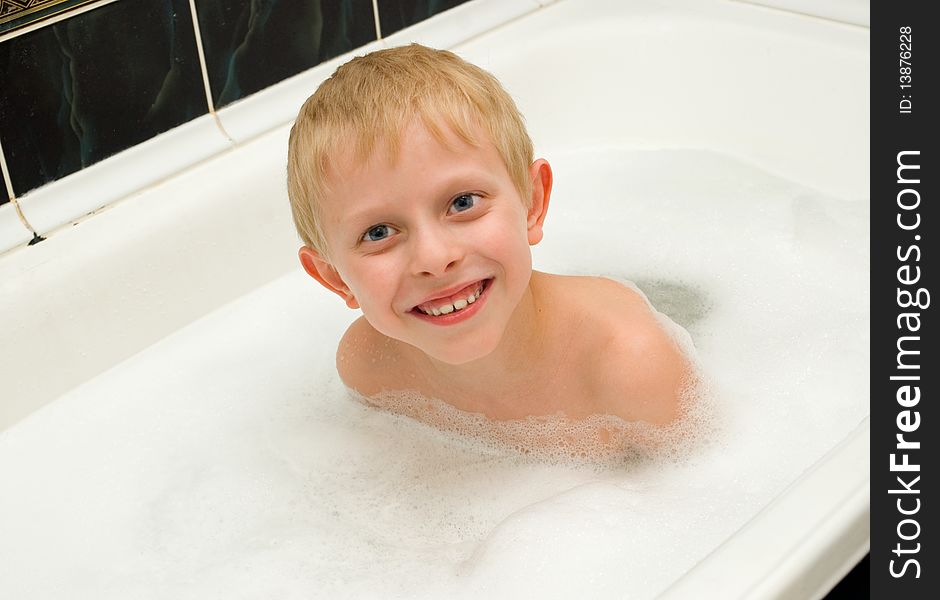 The boy bathes in a bathroom with foam