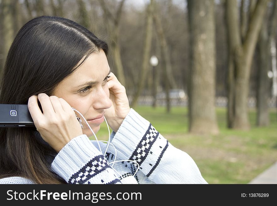 Beautiful girl in a park listening to music from your mobile phone