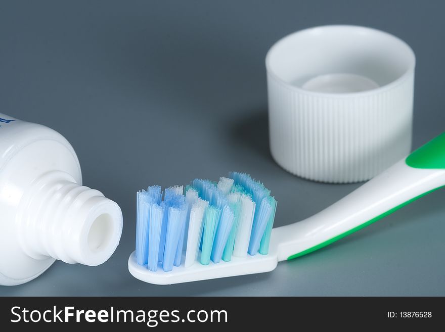 Toothbrush and toothpaste on gray background