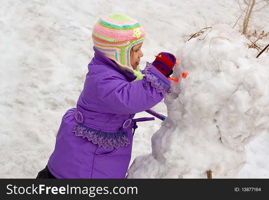 The little girl moulds the snowman