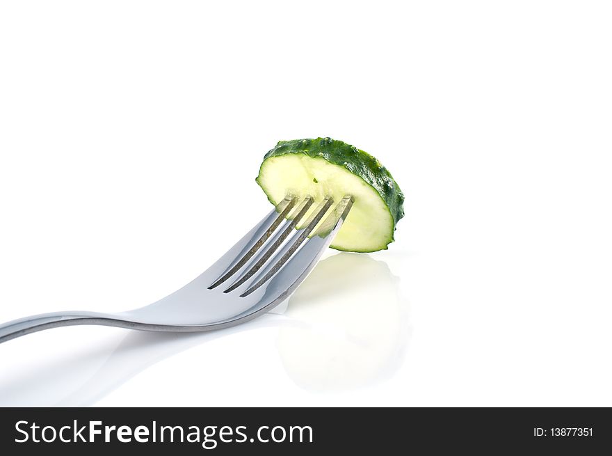 Piece of cucumber on the fork on white background