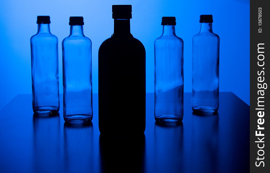Four little bottles behind a larger black one. Four little bottles behind a larger black one