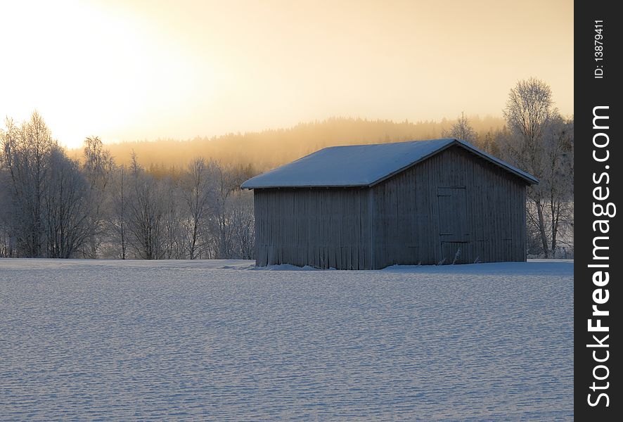 Old barn in cold winter sunrise