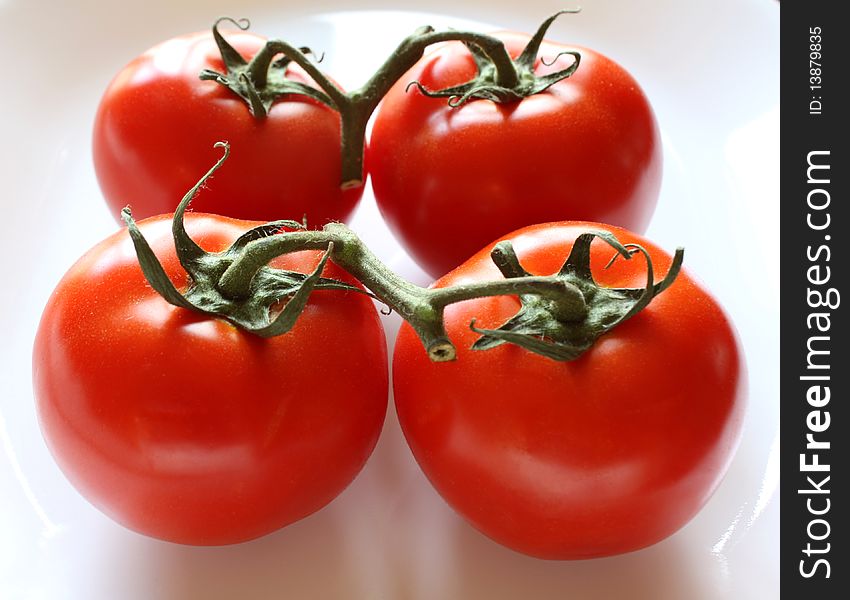 Two pairs of ripe red tomatoes on the vine. Two pairs of ripe red tomatoes on the vine.