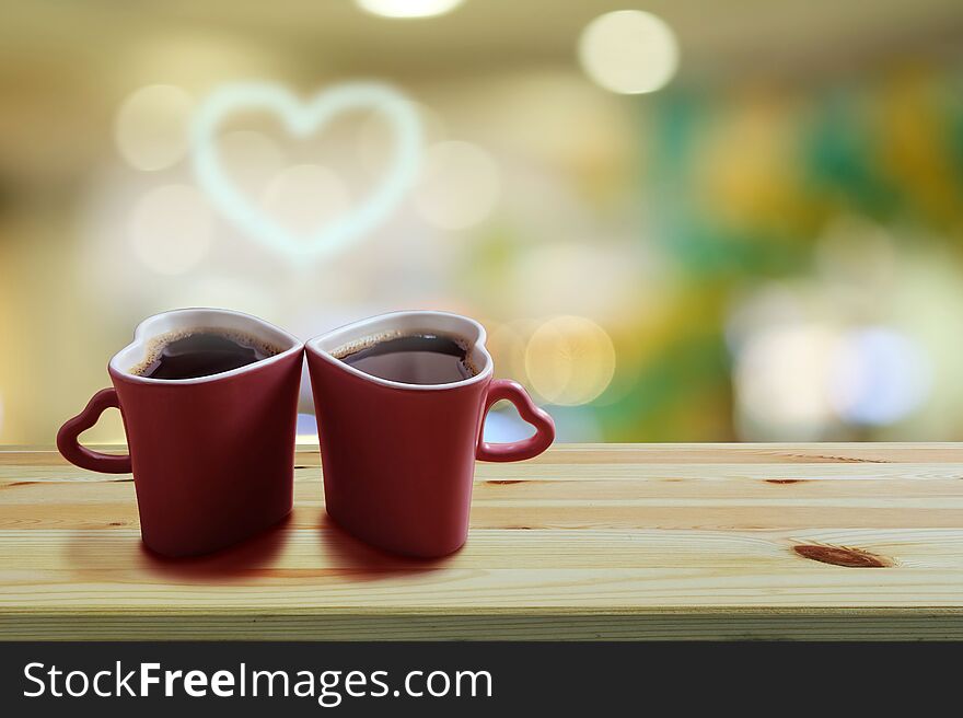 Black coffee in two pink cups heart shape with smoke is a heart shape on wooden floor and Colorful bokeh background