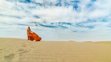 Girl Walks On Desert In Dress Fluttering In Wind. Beautiful Woman Is Walking, Staing On Sand Or Dune, Touches, Shows Her Stock Photos