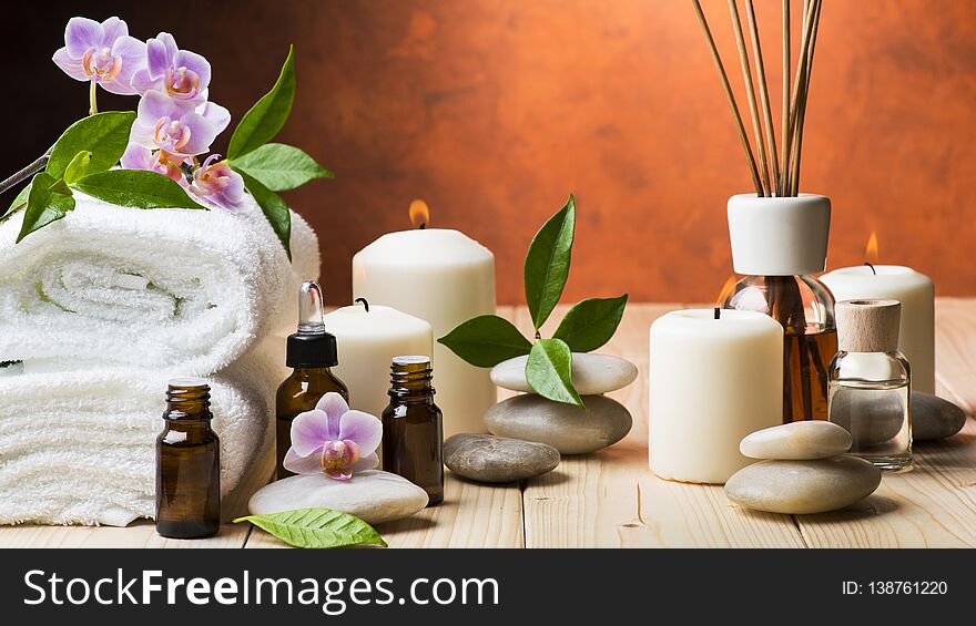Composition with orchid and jasmine flowers, some small bottles with essential oil, candles and light stones for massage. Composition with orchid and jasmine flowers, some small bottles with essential oil, candles and light stones for massage