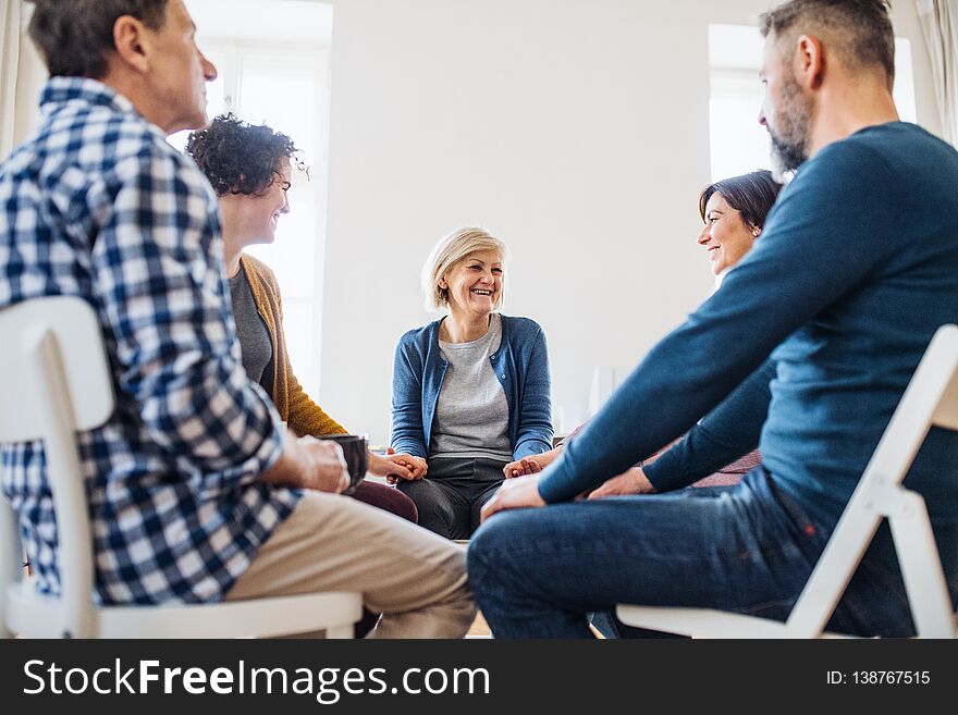 Men and women sitting in a circle and holding hands during group therapy.