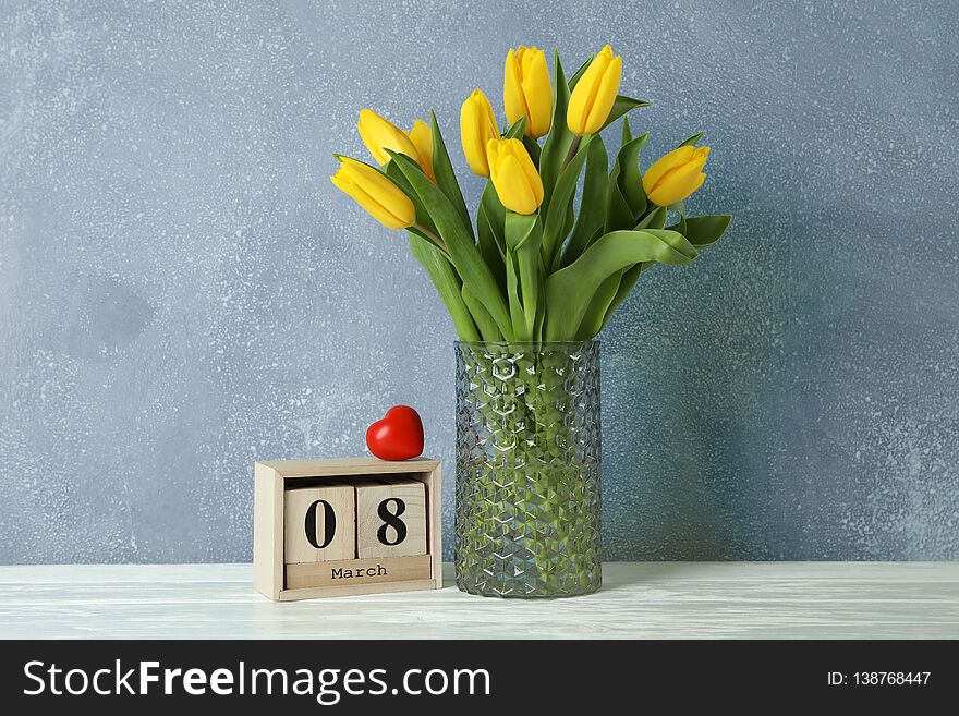 Beautiful yellow tulips in a glass vase on white background for Mother`s Day