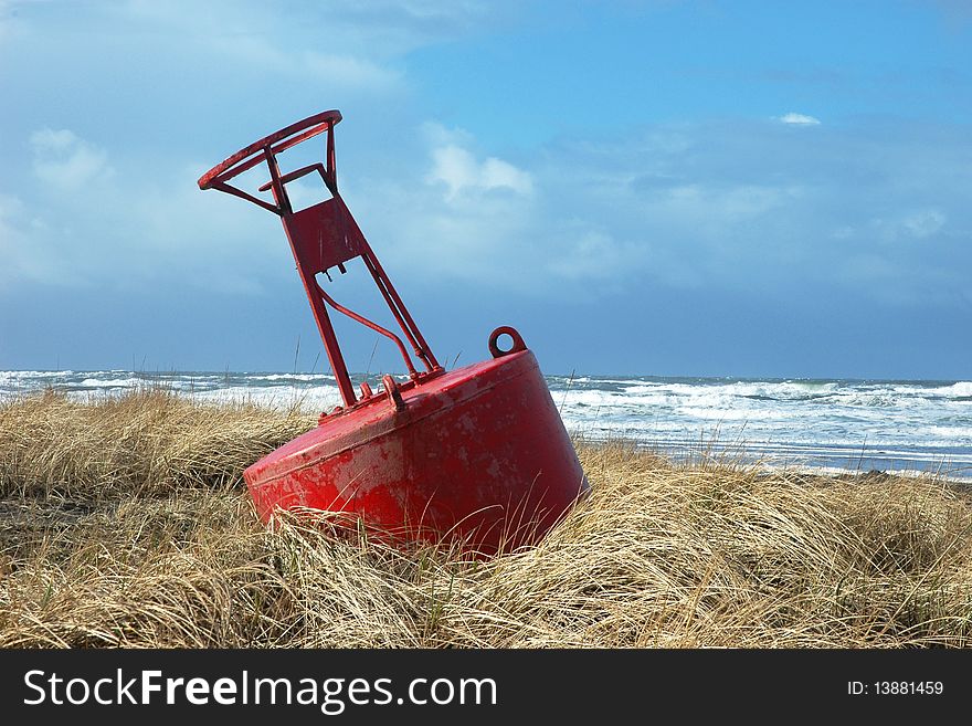 A large red buoy laying in sea grass on the beach at Long Beach Washington, USA