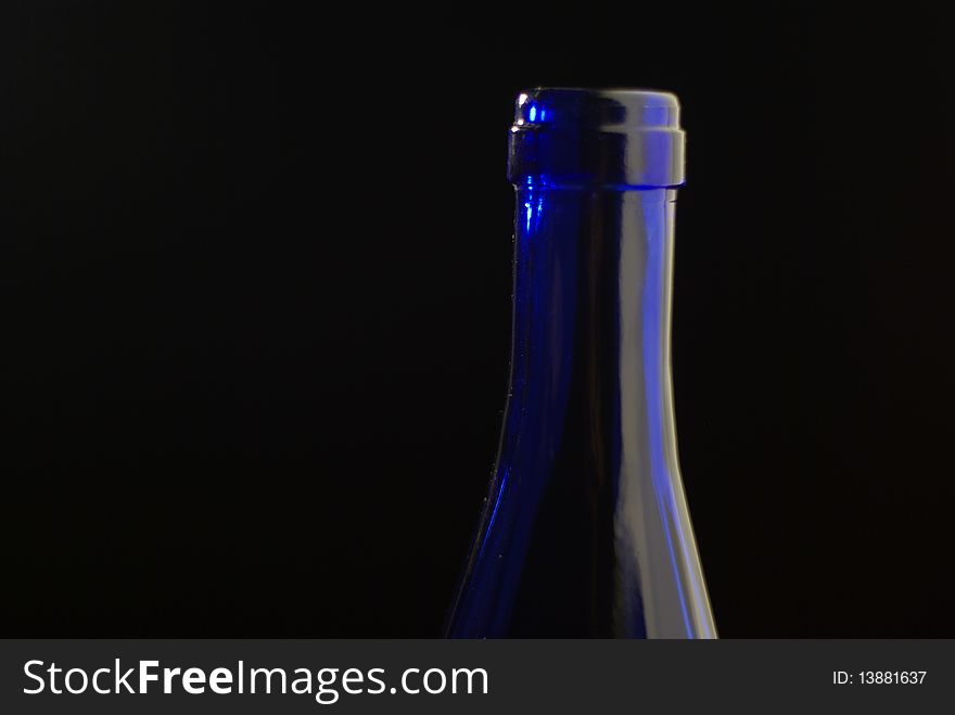 The neck of a blue glass botlle shot against a black background. The neck of a blue glass botlle shot against a black background.