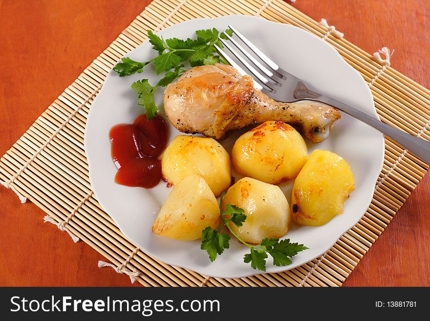 Roasted chicken leg with potatoes on dish and bamboo mat