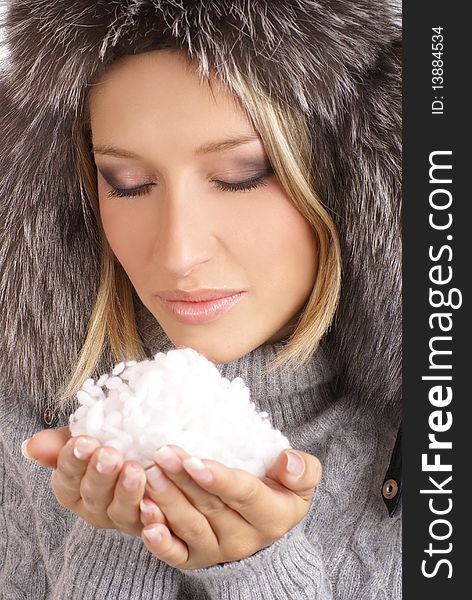 Portrait of a young and attractive blond with a winter hat holding snow in her hands. Portrait of a young and attractive blond with a winter hat holding snow in her hands.
