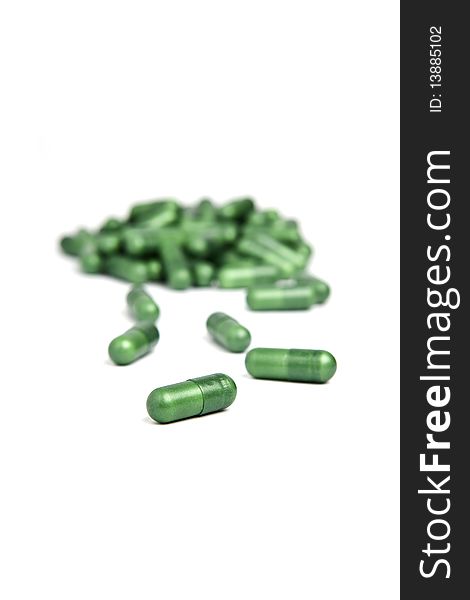 Green pills on a white background, shallow depth of field
