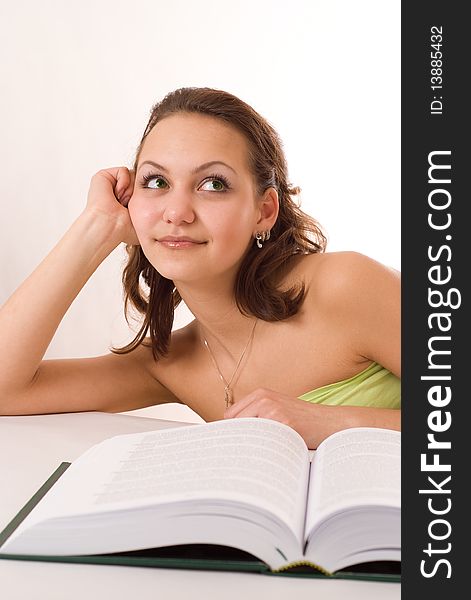 Pretty girl sitting at a table with a book on white background. Pretty girl sitting at a table with a book on white background