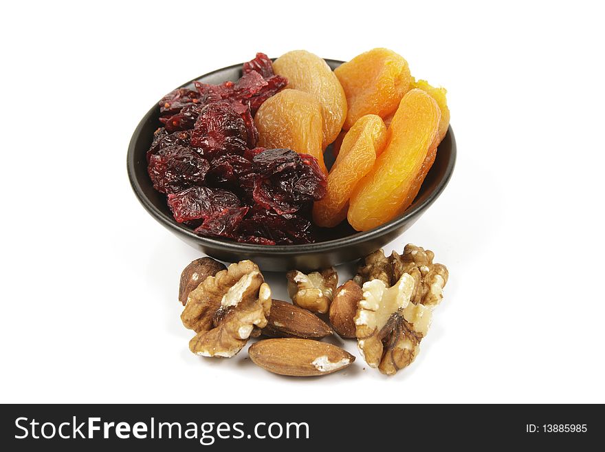 Red ripe dried cranberries and dried orange apricots with mixed nuts on a reflective white background. Red ripe dried cranberries and dried orange apricots with mixed nuts on a reflective white background