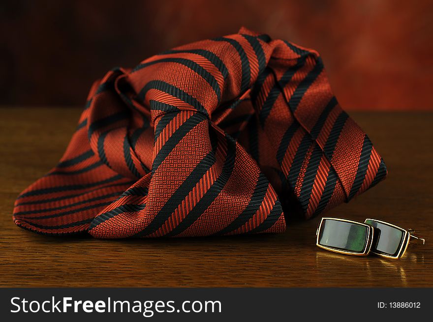 Tie and cuff button over a dark background