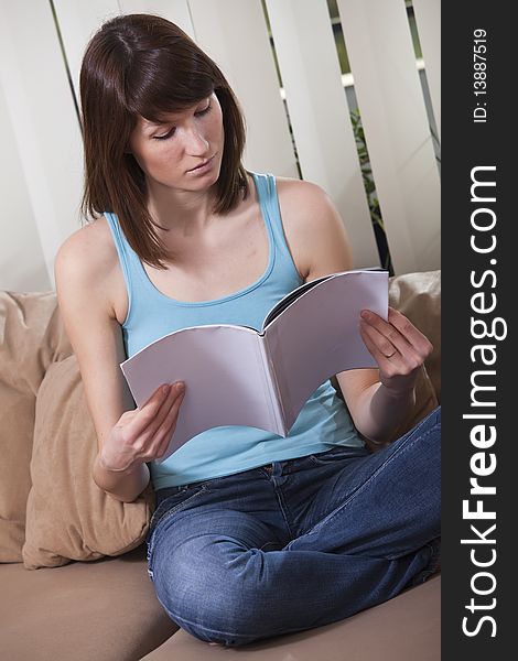 Woman reading magazine at home on the sofa. Woman reading magazine at home on the sofa