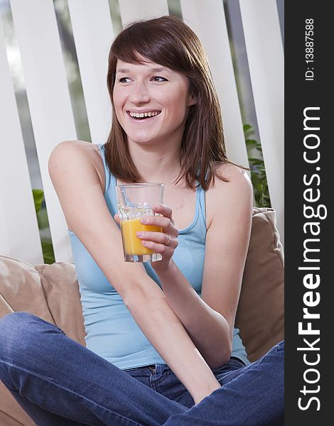 Happy woman sitting on the sofa with glass orange juice. Happy woman sitting on the sofa with glass orange juice
